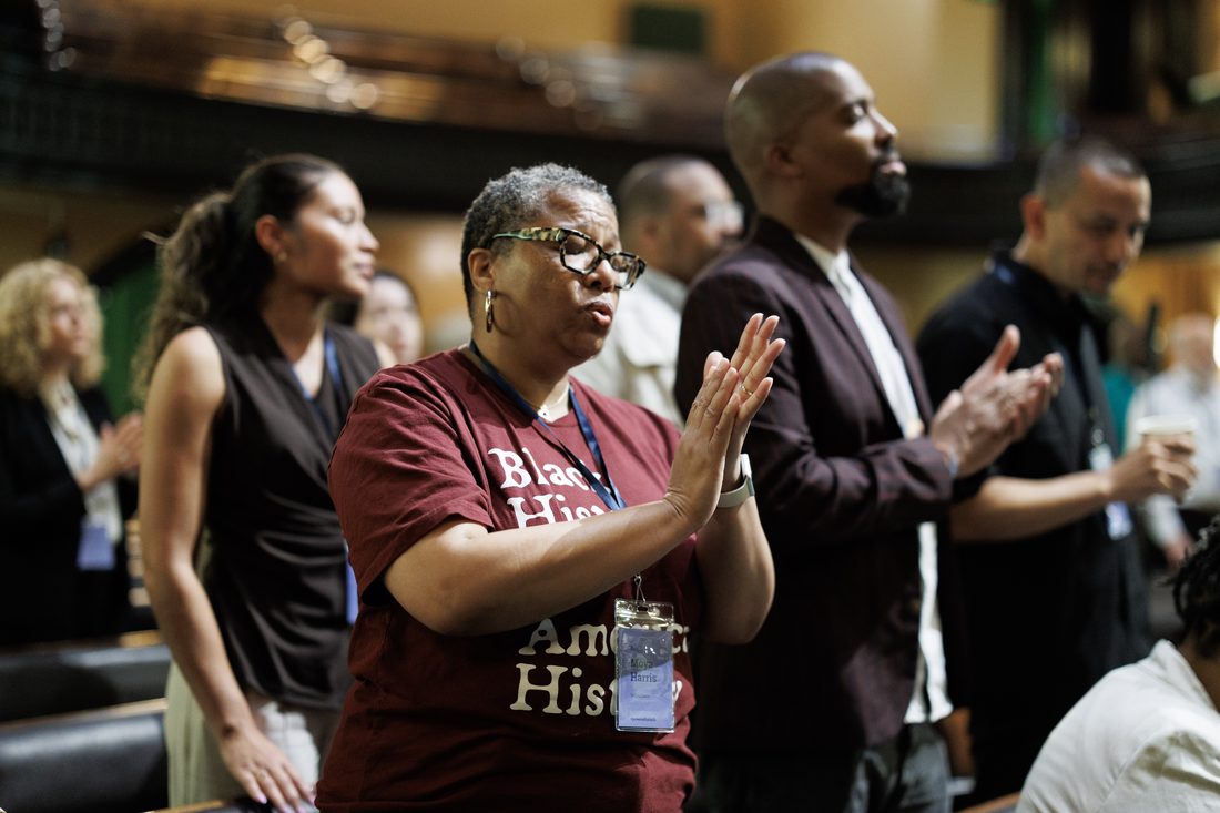 Participants standing and applauding during the convening