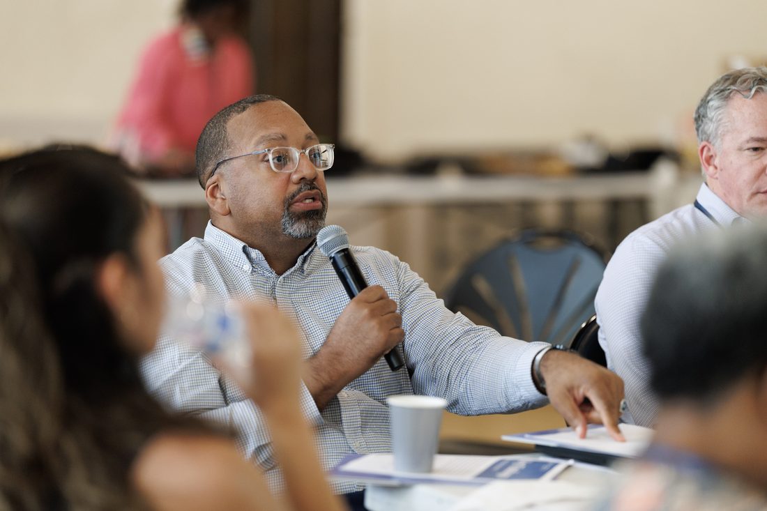 Clergy and leaders seated at work tables during a training session
